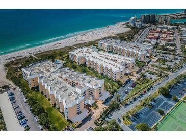 Expansive aerial view of the beachfront condominium complex with lush landscaping, parking, and beach access at 6500 Sunset Way # 202, St Pete Beach, FL 33706