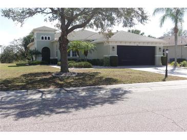 Inviting single-story home features a two-car garage, turret entrance, and mature landscaping for great curb appeal at 920 Regal Manor Way, Sun City Center, FL 33573
