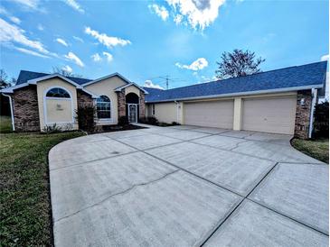 Spacious home with large driveway, 3-car garage, and brick and stucco exterior at 11040 Flicker Rd, Brooksville, FL 34613