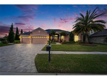 Charming home with a three-car garage, lush landscaping, and a brick-paved driveway at 2903 Marble Crest Dr, Land O Lakes, FL 34638