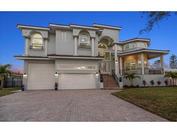 Stunning two-story home showcasing a three-car garage, red brick driveway, and lush landscaping at 124 Leeward Is, Clearwater Beach, FL 33767