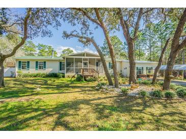 Charming single story home with screened porch, green shutters and well maintained landscaping at 17480 Nuthatch Rd, Weeki Wachee, FL 34614