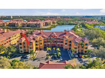 Beautiful aerial view of a waterfront condo building with red tile roof, lush landscaping, and surface parking at 2717 Via Cipriani # 620A, Clearwater, FL 33764