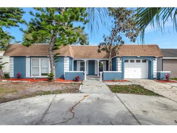 Charming one-story home with a two-car garage, featuring a well-maintained yard with mature trees and landscaping at 3544 Landale Dr, Holiday, FL 34691