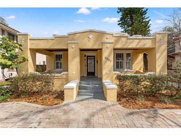 Charming yellow stucco bungalow featuring a welcoming front porch and well-maintained landscaping at 5807 N Branch Ave, Tampa, FL 33604