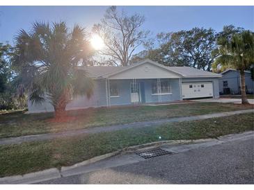 Charming single-story home with updated brickwork, front porch, attached garage and palm tree in the front yard at 6008 Memorial Hwy, Tampa, FL 33615