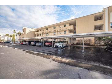 Condo parking area with covered spaces and well-maintained landscaping around the residential building at 7465 Bay Island S Dr # 318, South Pasadena, FL 33707