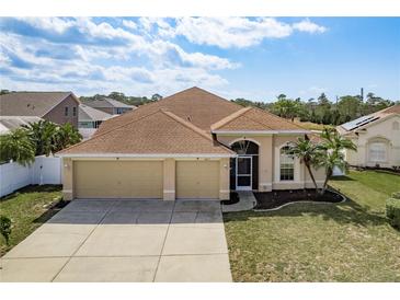 Charming single-Gathering home showcasing a three-car garage, mature landscaping, and a welcoming entryway at 2619 Ravendale Ln, Holiday, FL 34691