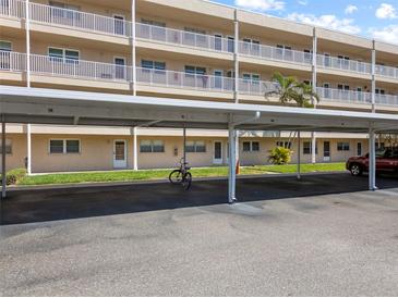 Exterior view of condo building showcasing covered carport parking and manicured lawn at 9950 62Nd N Ter # 203, St Petersburg, FL 33708