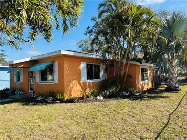 Charming orange single-story home with manicured lawn, lush landscaping, and turquoise awning at 1818 53Rd S St, Gulfport, FL 33707