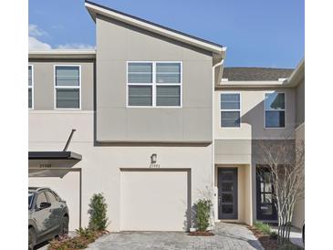 Modern townhouse featuring a two-car garage, clean architectural lines, and minimal landscaping at 25993 Woven Wicker Bnd, Lutz, FL 33559