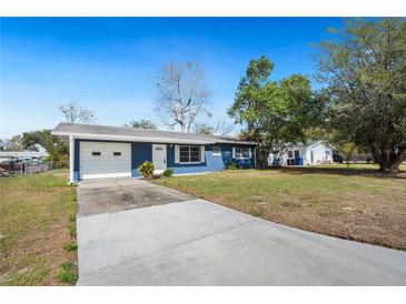 Charming blue single-story home featuring a long driveway, front lawn, and attached single-car garage at 39035 Citadel Cir, Zephyrhills, FL 33542