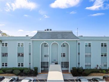 Charming condo building featuring arched entryway, lush landscaping, and ample parking for residents and guests at 1706 Belleair Forest Dr # 348, Belleair, FL 33756