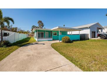 Charming turquoise home featuring a covered carport and spacious front yard with a long private driveway at 3774 Arkansas Ne Ave, St Petersburg, FL 33703