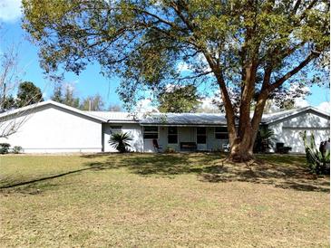 A single story home with an attached garage, a metal roof, and a well manicured lawn at 39349 & 39343 Rusbe Dr, Zephyrhills, FL 33540