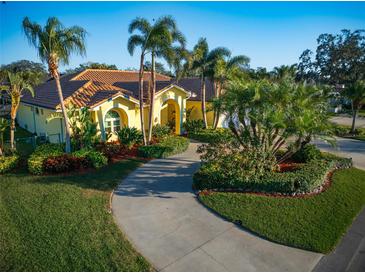 Beautiful yellow home with lush landscaping and a circular driveway lined with palm trees at 109 Live Oak Ln, Largo, FL 33770