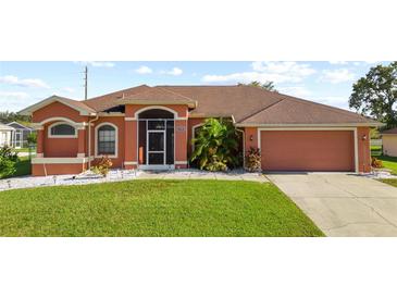 Charming single-story home featuring a well-manicured lawn, two car garage, and a screened in front entryway at 13481 Pullman Dr, Spring Hill, FL 34609