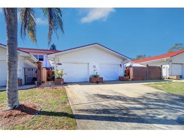 Charming single-story villa with a white exterior, two-car garage, and well-maintained front yard at 1411 Water View W Dr, Largo, FL 33771
