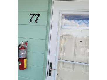 Unit #77 front door with a fire extinguisher mounted on the siding, and a storm door at 2043 Denmark St # 77, Clearwater, FL 33763