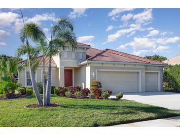 Lovely single-story home with a three-car garage, landscaped lawn, and a welcoming red front door at 6214 45Th E Ln, Bradenton, FL 34203