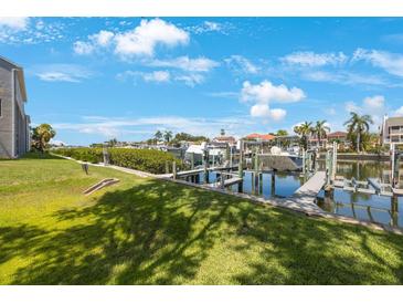 View of a private boat dock on a sunny day with tropical landscaping and clear blue skies at 1125 Pinellas Bayway S # 305, St Petersburg, FL 33715