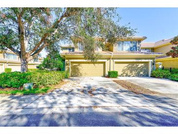 Charming townhome featuring a two-car garage, complemented by lush landscaping and mature trees at 12607 San Blas Loop, Largo, FL 33774