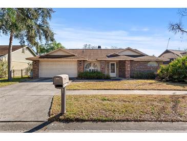 Charming single-story home with brick facade, mature landscaping, and an attached two-car garage at 14917 Barby Ave, Tampa, FL 33625