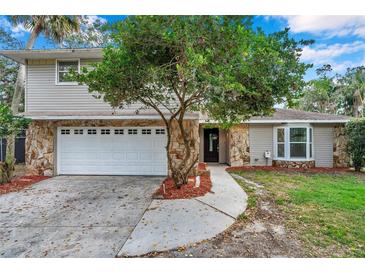 Two story home featuring a stone facade, a two car garage, manicured lawn, and a mature tree at 2151 E Leewynn Dr, Sarasota, FL 34240