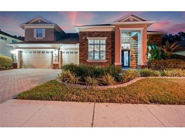 Beautiful two-story home featuring a well-manicured lawn and a three-car garage at twilight at 21537 Draycott Way, Land O Lakes, FL 34637