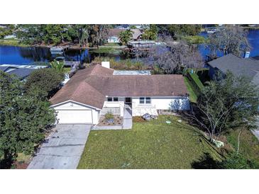 Aerial shot of a lakeside property with a well-manicured lawn, mature trees, and a private lake access at 3046 Lake Padgett Dr, Land O Lakes, FL 34639