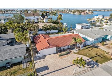 Beautiful waterfront home featuring a red tile roof, brick driveway, and lush tropical landscaping at 619 59Th Ave, St Pete Beach, FL 33706