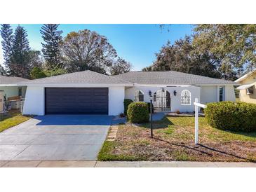 Charming single-story home with a black garage door and a gated front entrance at 714 Lemonwood Dr, Oldsmar, FL 34677