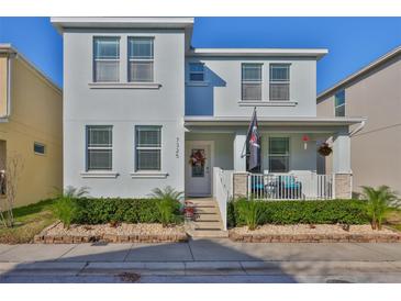 Charming two-story home featuring a cozy front porch, decorative landscaping, and a freshly painted facade at 7325 S Trask St, Tampa, FL 33616