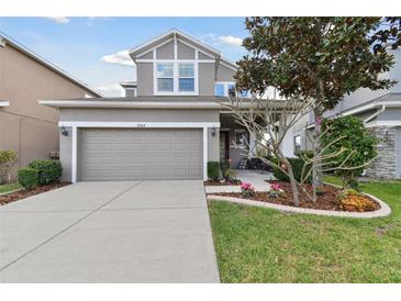 Two-story home boasts a manicured front yard, gray siding and a two-car garage at 7645 Windchase Way, Wesley Chapel, FL 33545