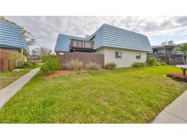 Charming home exterior featuring a unique blue roof, well-maintained lawn, and a cozy second-story balcony at 14505 Catalina Cir, Seminole, FL 33776