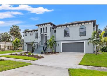 Stunning gray two-story home with a two-car garage, landscaped yard, and a stairway leading to the front door at 58 Inness Dr, Tarpon Springs, FL 34689