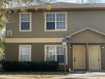 Two-story townhouse exterior with a tan exterior, multiple windows, and a handicap parking sign at 5924 Brickleberry Ln # 101, Zephyrhills, FL 33541