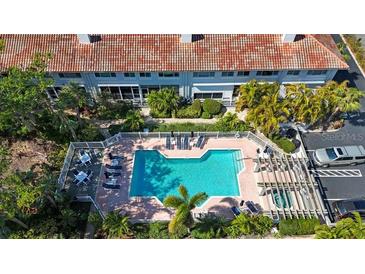 Aerial view of a community pool and hot tub surrounded by lush mature trees and lounge chairs at 903 Pinellas Bayway S # 307, Tierra Verde, FL 33715