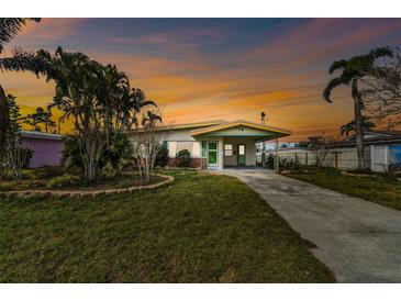 Charming single-story home featuring mature landscaping and a covered carport on a large lot with a sunset in the sky at 969 Britton St, Largo, FL 33770