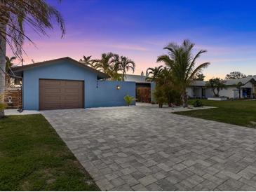 Charming single Gathering home featuring a patterned brick driveway, lush landscaping, and an attached garage at 114 12Th St, Belleair Beach, FL 33786