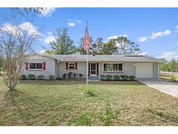 Charming single-story home with well-maintained lawn, landscaping, and American flag at 14350 Hill Country Rd, Brooksville, FL 34614