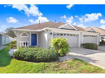 Charming single-story home featuring a blue front door, well-manicured lawn, and attached two-car garage at 19131 Weymouth Dr, Land O Lakes, FL 34638