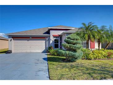 Charming single-story home with a two-car garage, colorful landscaping, and a well-maintained lawn at 2112 Purple Orchid Pl, Ruskin, FL 33570