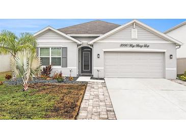 Charming single-story home featuring a two-car garage, modern landscaping, and well-maintained lawn at 8990 Forge Breeze Loop, Wesley Chapel, FL 33545