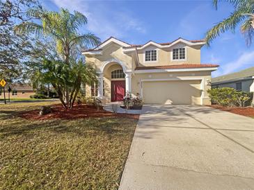 Charming two-story home featuring a red-tiled roof, arched entry, and lush tropical landscaping at 9003 Willowbrook Cir, Bradenton, FL 34212