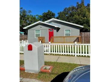 Charming single-story home featuring a red front door, a spacious porch and a white picket fence at 910 Seminole St, Clearwater, FL 33755