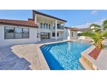 Back exterior featuring a private pool with a waterfall feature, travertine tile deck, and covered patio at 912 Symphony Beach Ln, Apollo Beach, FL 33572