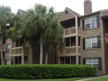 Charming condo building featuring a brick facade, multiple balconies, and lush landscaping at 10200 Gandy N Blvd # 209, St Petersburg, FL 33702