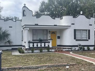 Charming Spanish style home features unique architectural details, a yellow door, and a well manicured front yard at 2613 E 23Rd Ave, Tampa, FL 33605
