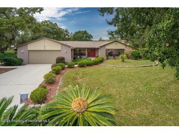 Charming home with a well-manicured front lawn, a two car garage, and a welcoming red front door at 5443 Ott Ct, Spring Hill, FL 34608